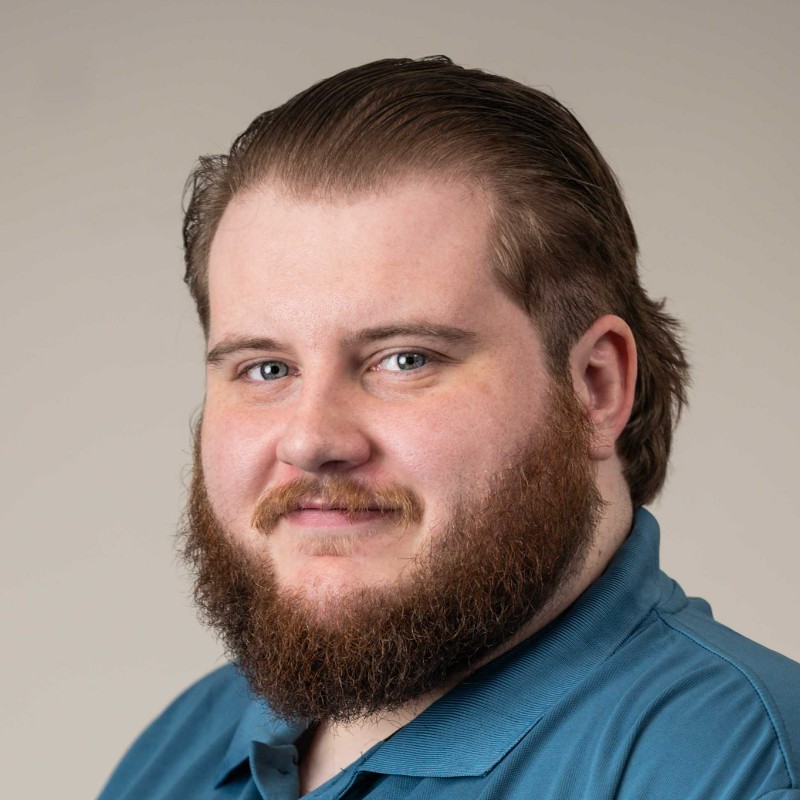 Image of Alexander Mason,s a man with short brown beard, mustache, hair slicked back, and a blue collared polo shirt.